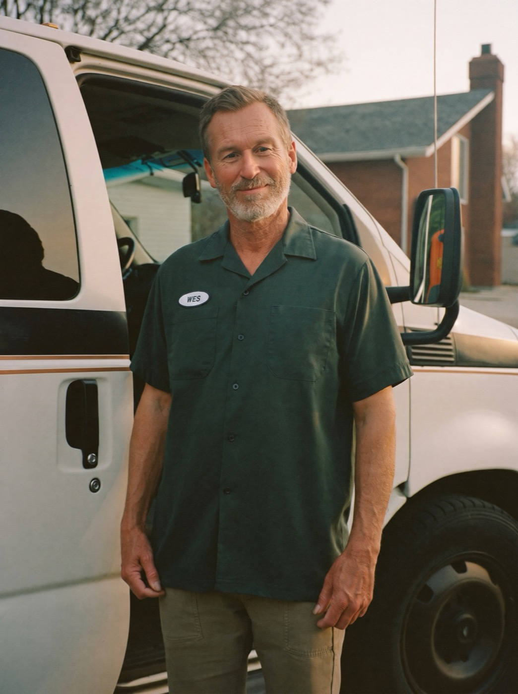 Wes Langford, the fictional owner, standing at the open door of his green-and-white work van in morning light